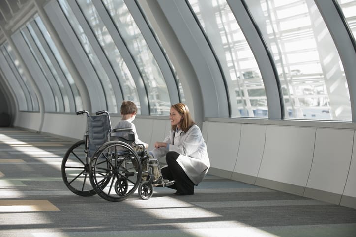 Photo shows a doctor speaking to a young boy in a wheelchair/Getty Images
