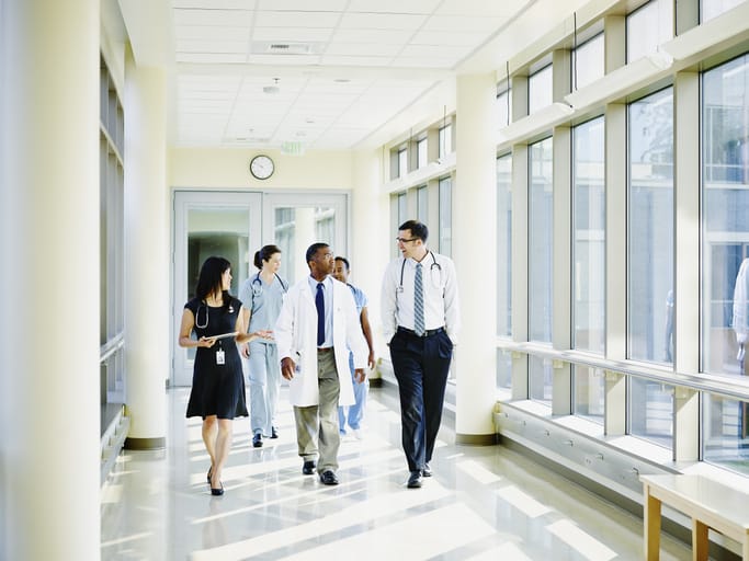 Photo shows a team of doctors and medical staff walking through a hospital corridor/Getty Images
