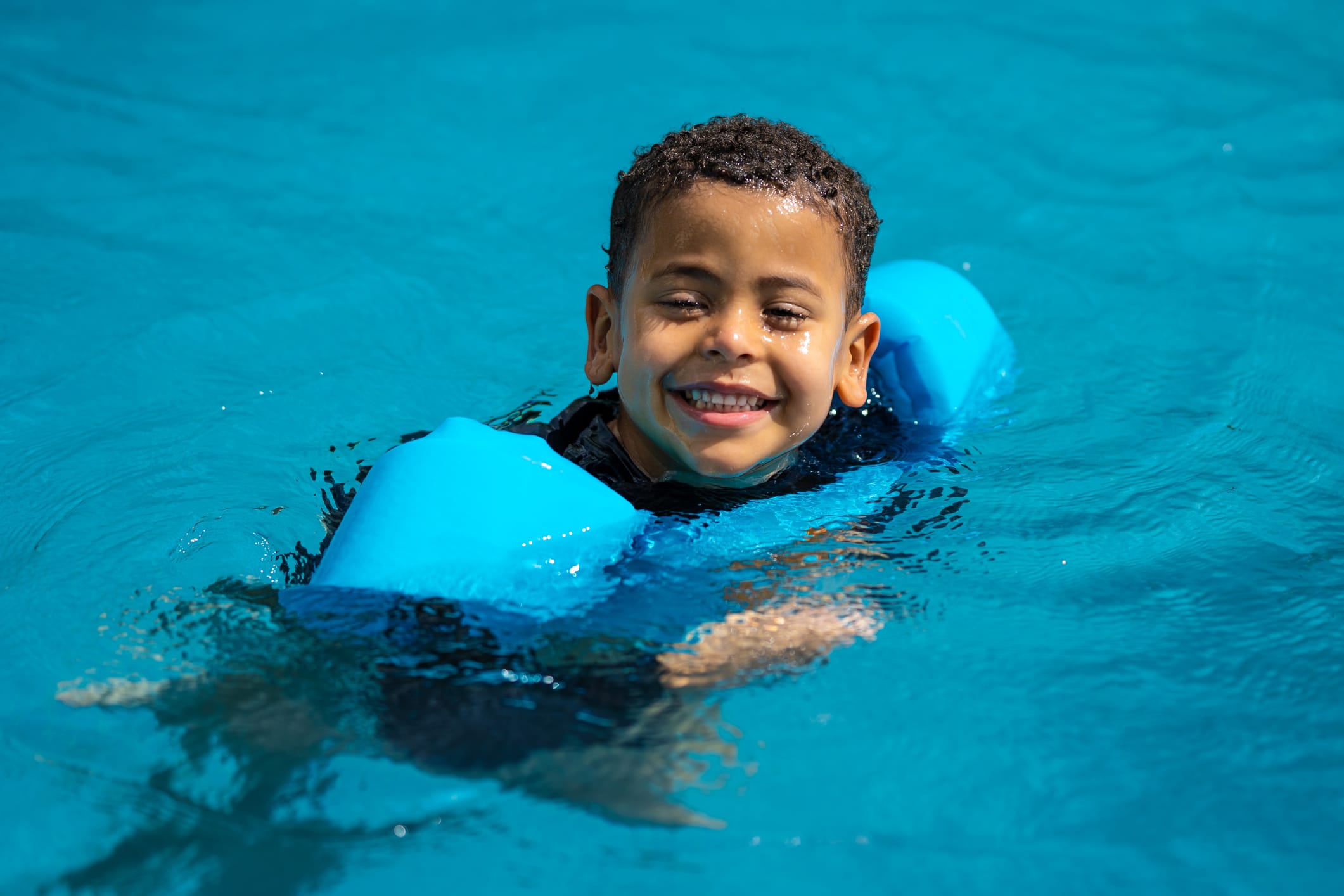 Photo of boy in pool wearing arm floatation