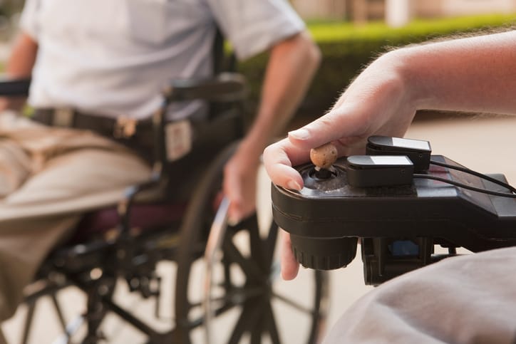 Photo shows a man with DMD controlling his wheelchair with his hand/Getty Images
