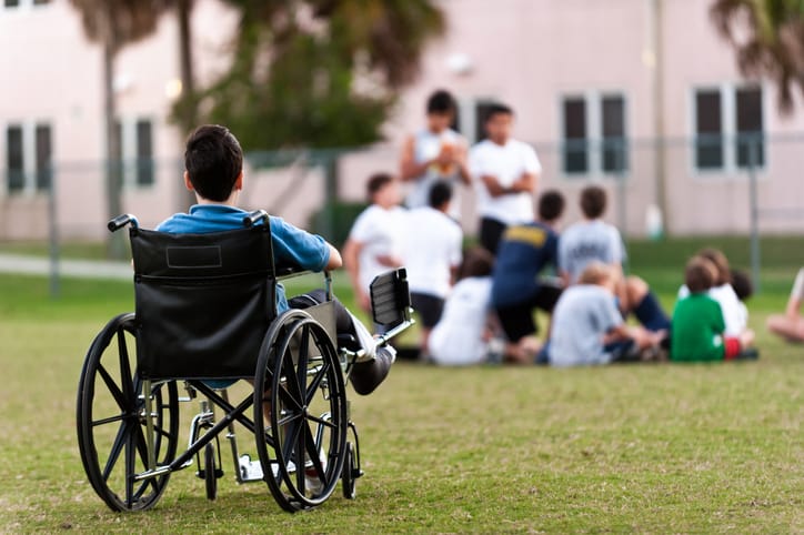 Photo shows a boy in a wheelchair watching other children play/Getty Images