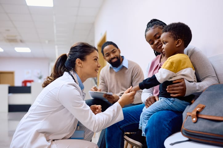 Photo shows a pediatrician talking to a little boy and his family/Getty Images