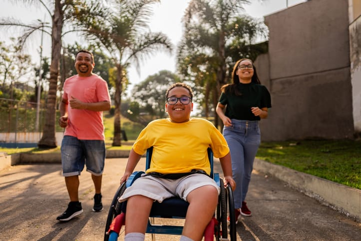 Photo of parents running alongside son in wheelchair