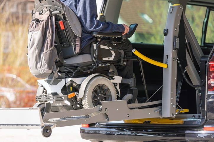 Accessible car with wheelchair lift ramp for person with disability.