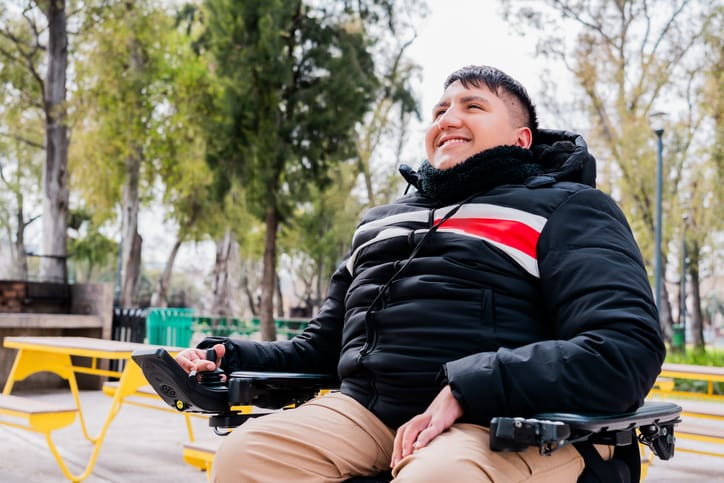 Young wheelchair man contemplating in a public park