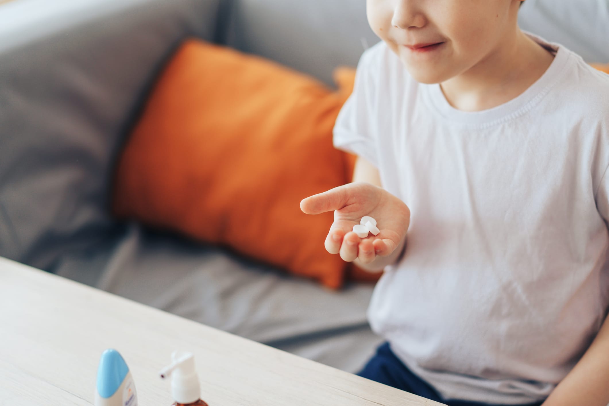 Boy holding three round pills in his palm.