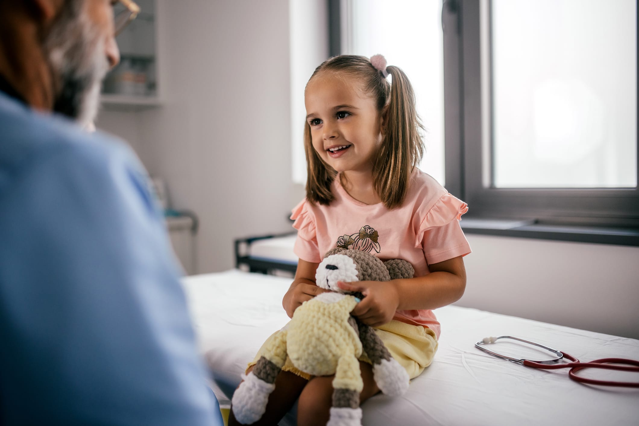 A male pediatrician examines a little girl in his office