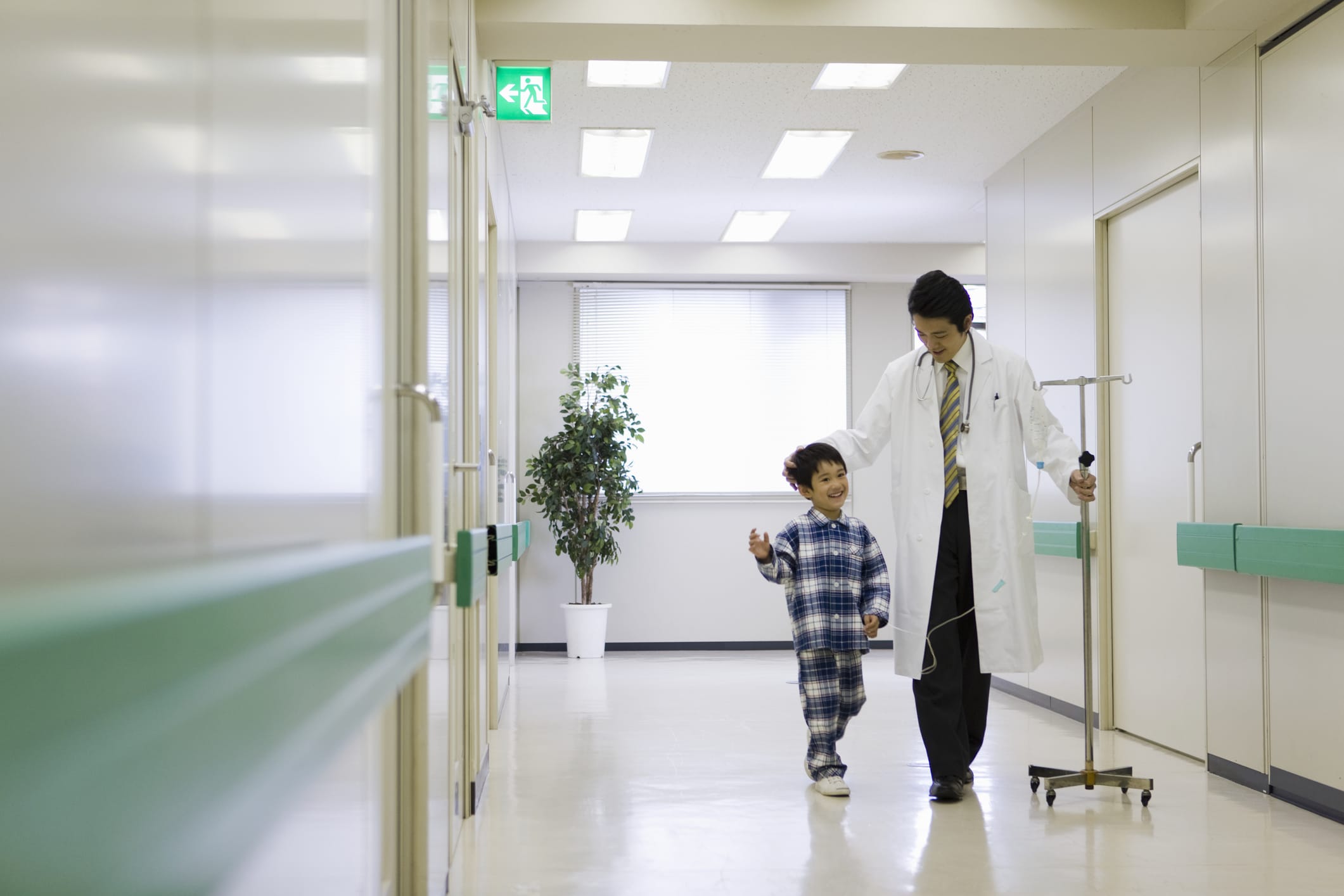 Doctor with medicine drip, walking with boy in hospital corridor