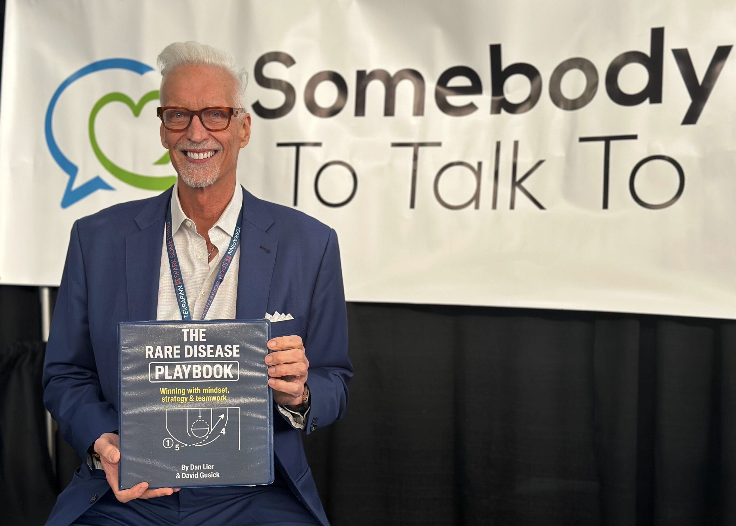 Dan Lier holding a copy of the "Rare Disease Playbook" at the 2025 World Orphan Drug Congress in Boston