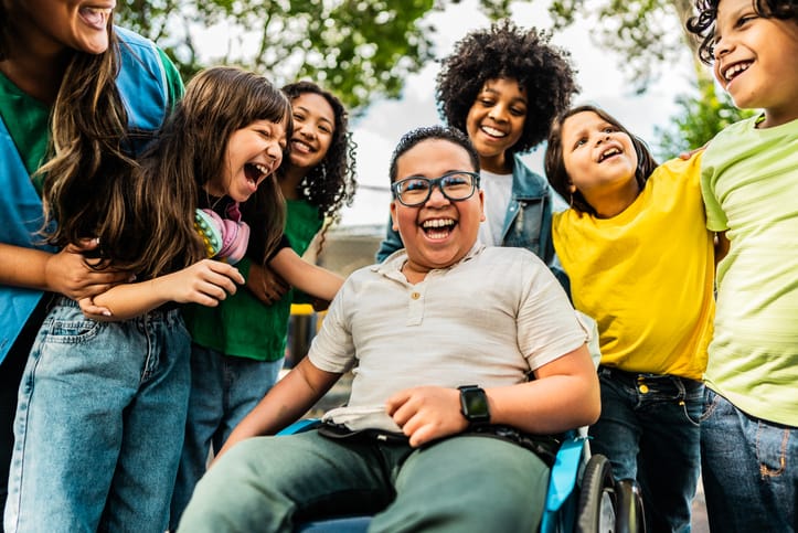 Boy in a wheelchair smiling with friends