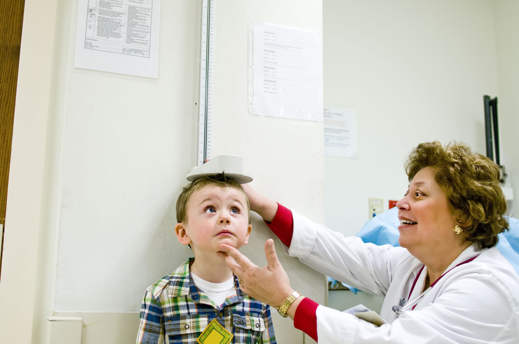 Female doctor checking height of young boy