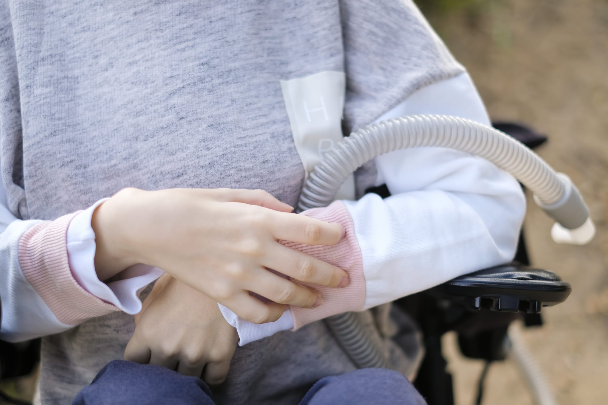 Hands of a disabled person with muscular dystrophy holding a ventilator for deep breathing