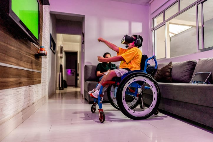 Boy in wheelchair playing video games at home