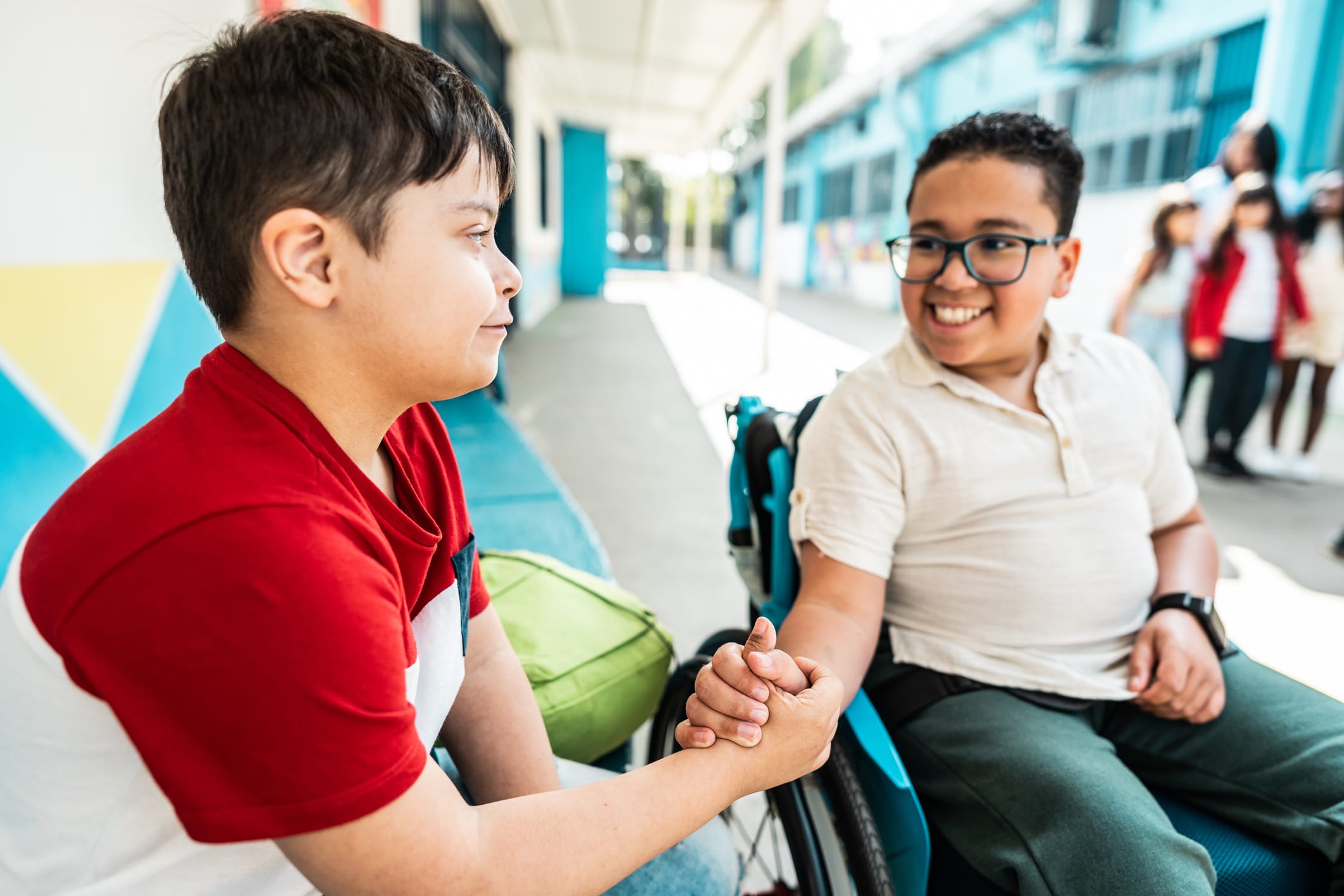 Boy in wheelchair holding hands with boy with Downs syndrome