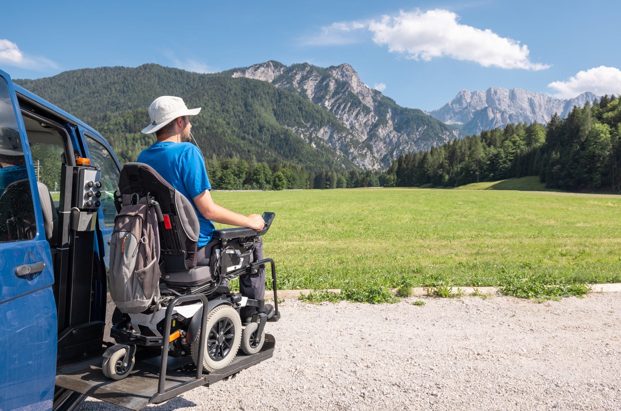Man in wheelchair leaving accessible van with mountains in background